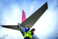 Airside engineer talking on radio near aircraft on runway, low angle view